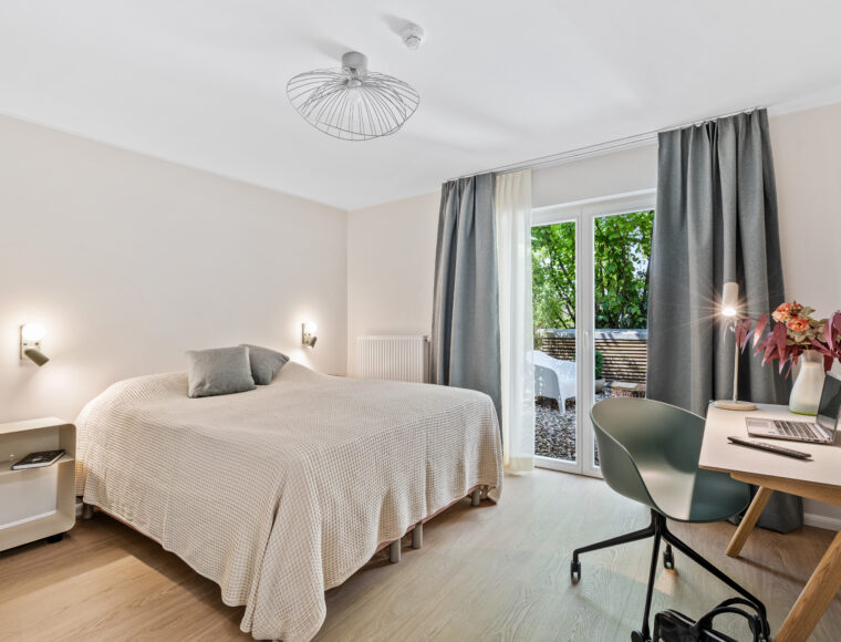 A minimalist bedroom at Keyinn Serviced Residences in Belair, with a cozy double bed, soft beige bedding, and wall-mounted lamps.