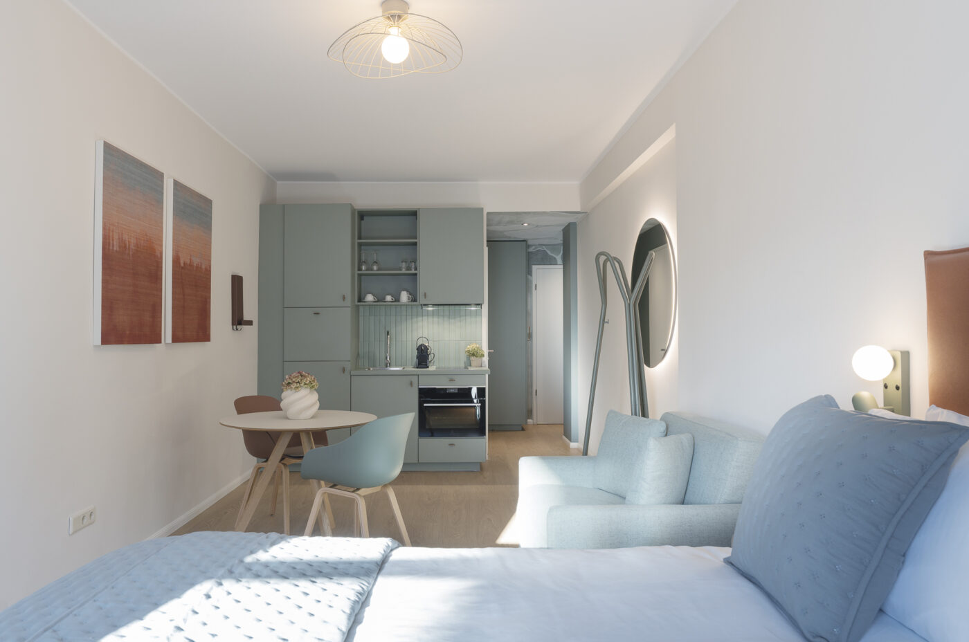 Keyinn Serviced Residences Belair studio with a blue theme, bed, and sofa. The space includes a kitchenette, dining table, and integrated lighting.