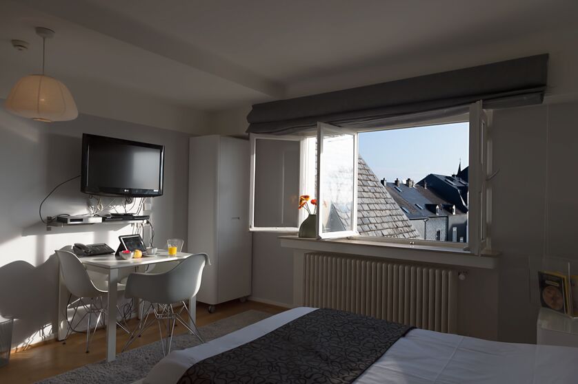 Keyinn Serviced Residences apartment featuring a double bed, a wall-mounted TV, and a small dining table. Room shows large window provides a scenic view.