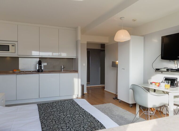 Keyinn Serviced Residences studio featuring a kitchenette, a single bed with a patterned throw, and a dining setup. A wall-mounted TV is included.