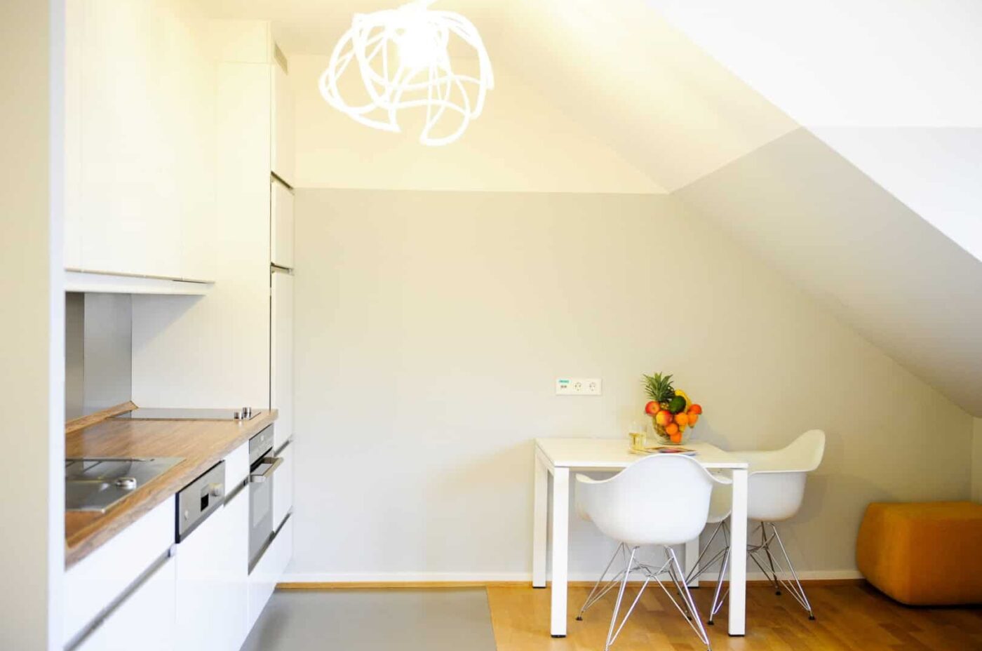 Keyinn Serviced Residences apartment dining space & kitchen with white cabinets, wood countertops, with a dining set & fruit bowl.