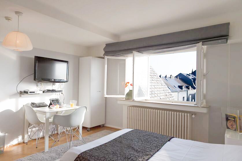 Keyinn Serviced Residences apartment featuring a double bed, a wall-mounted TV, and a small dining table. Room shows large window provides a scenic view.